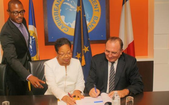 Patricia McKenzie (centre), CDB Vice-President, Operations and Eric de la Moussaye (right), French Ambassador to the Organisation of Eastern Caribbean States and Barbados, sign the Credit Facility Agreement. Looking on is Dave Waithe, Legal Counsel a